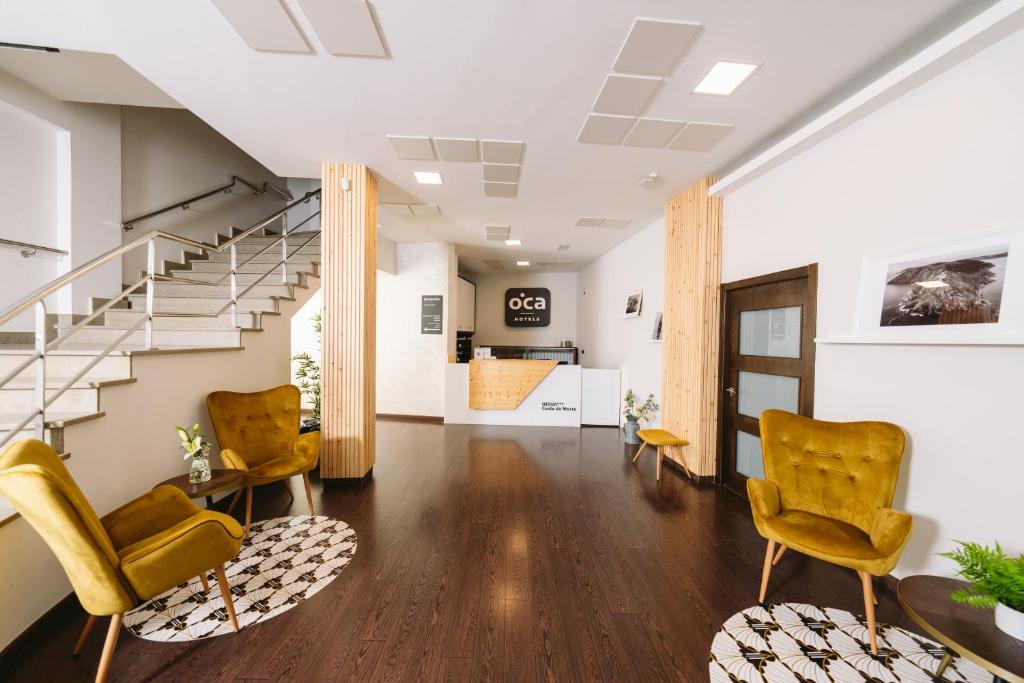 ein Wohnzimmer mit 2 Stühlen und einer Treppe in der Unterkunft Hotel Oca Insua Costa da Morte in Cee