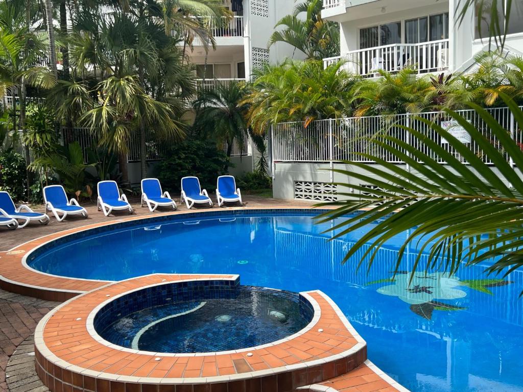 a swimming pool with chairs and a palm tree at Cascade Gardens Apartments in Gold Coast
