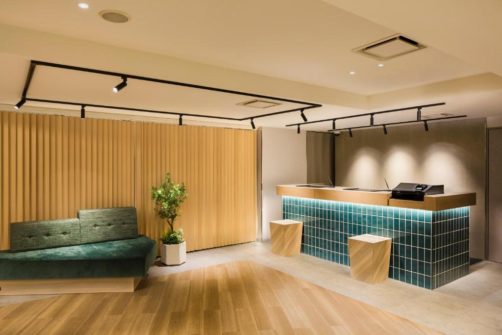 a lobby with a green couch and a counter at Tokyu Stay Shibuya Shin-Minamiguchi in Tokyo