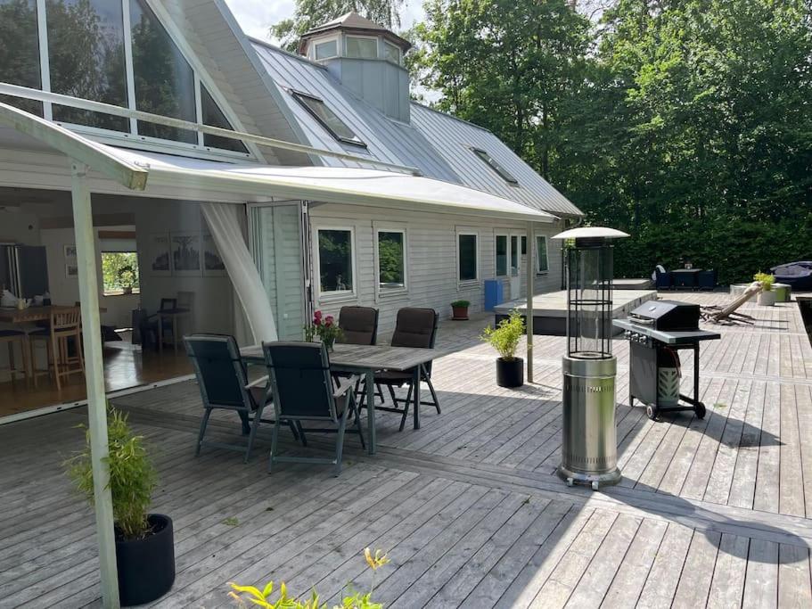 een patio met een tafel en stoelen en een grill bij Lugn och lummig oas för den stora familjen, söndag -söndag in Båstad