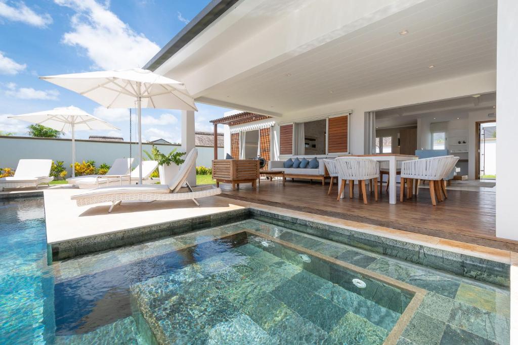 Cette maison dispose d'une piscine et d'une terrasse avec une table et des chaises. dans l'établissement VILLA LILOU, Splendide villa au centre de Grand Baie, à Grand Baie