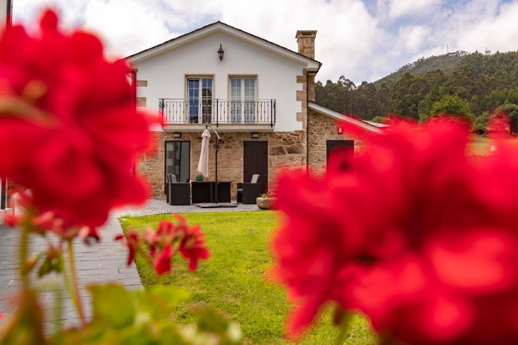 une maison avec des fleurs rouges devant elle dans l'établissement Casa Xan, à Jove