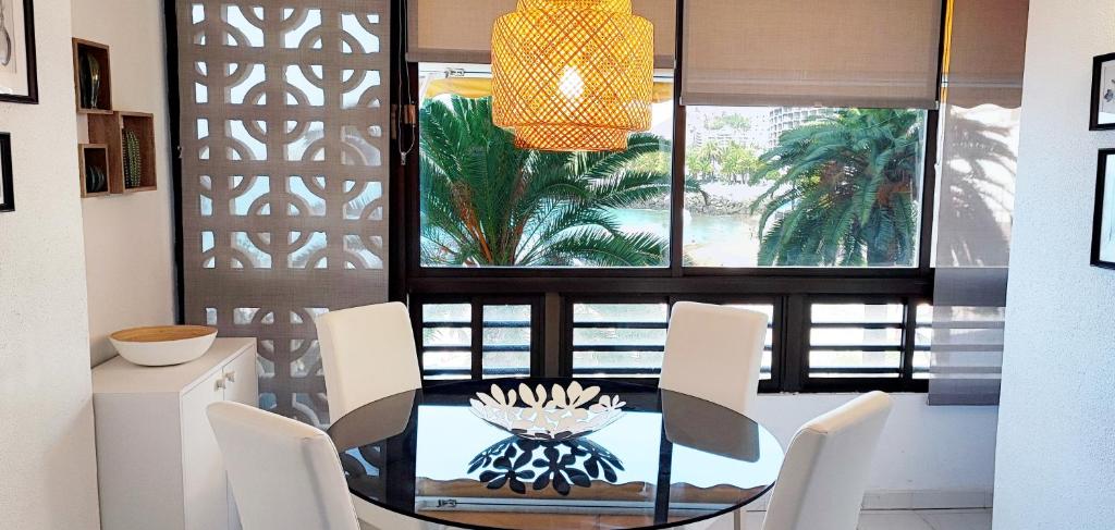 ein Esszimmer mit einem Glastisch und weißen Stühlen in der Unterkunft Doñana Apartamento Sunset first line to the beach in Patalavaca