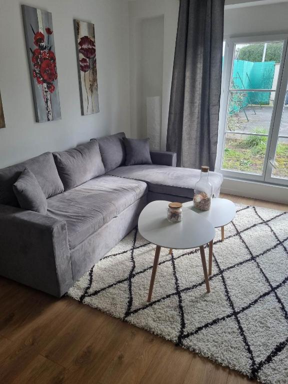 una sala de estar con un sofá y una mesa en The Grey studio, en Saint-Michel-sur-Orge