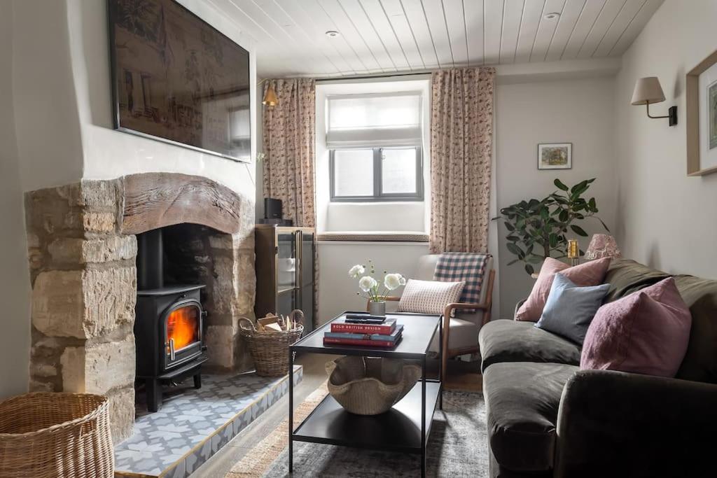 a living room with a couch and a fireplace at Whitsun Cottage in Stow on the Wold