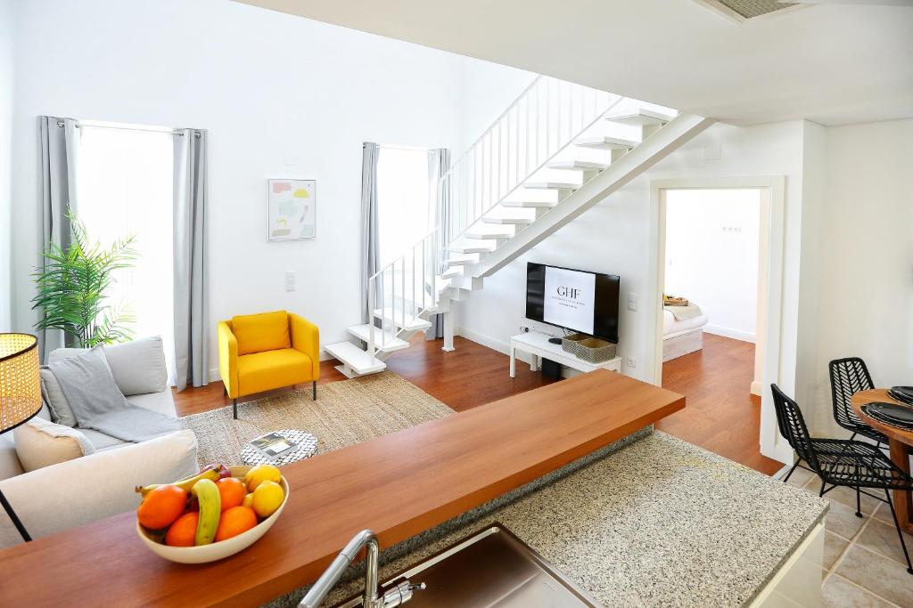 a living room with a table and a living room with stairs at Querido Algarve Apartment in Faro