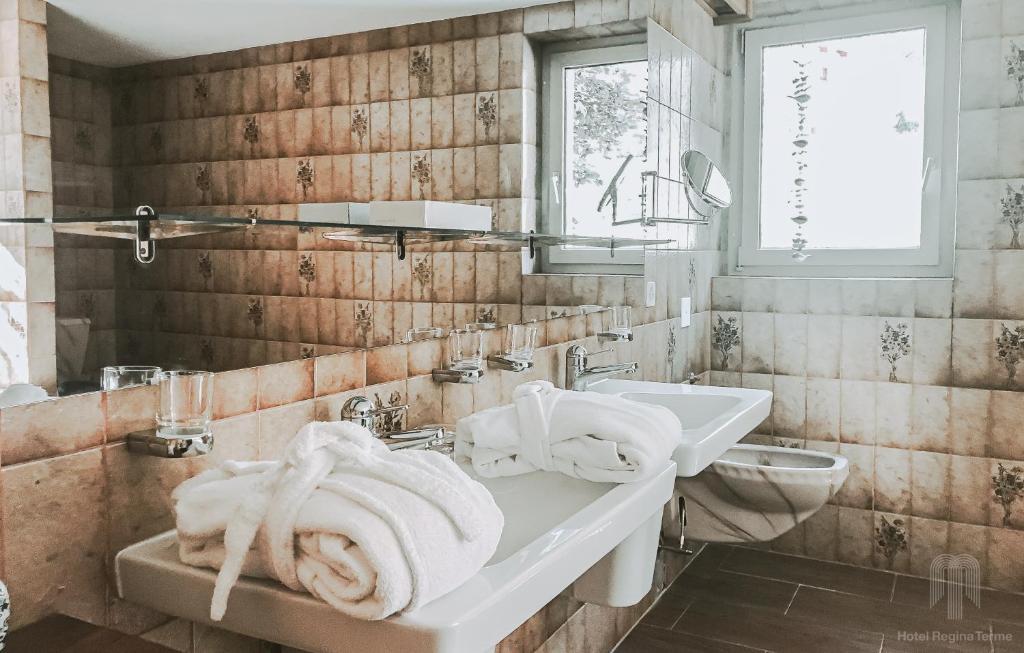een badkamer met een wastafel, een toilet en handdoeken bij Thermalhotel Regina Terme in Leukerbad