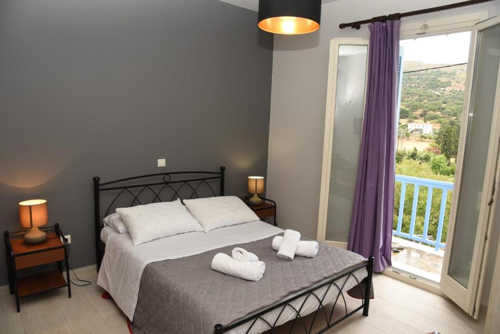 1 dormitorio con 1 cama con 2 toallas en Andros Guesthouses, en Ándros