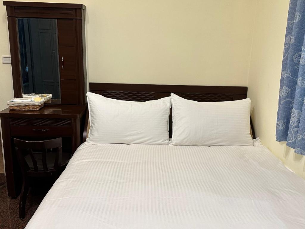 een slaapkamer met een bed met witte lakens en een tafel bij 偕安民宿 in Hualien