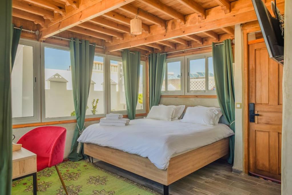 um quarto com uma cama grande e cortinas verdes em Stella 4 - studio deluxe, rooftop en médina em Essaouira
