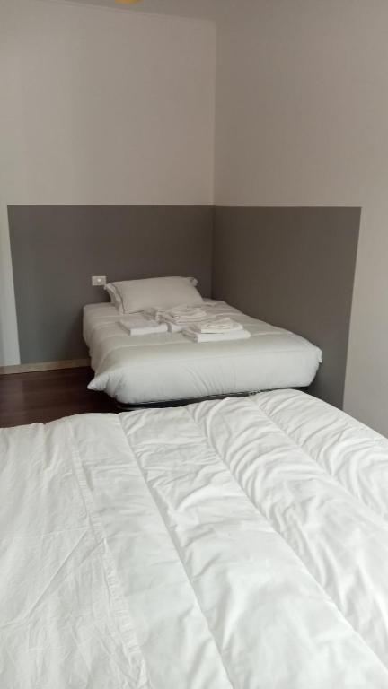 dwa białe łóżka w pokoju ze ścianą w obiekcie Casa Belzoni w Padwie