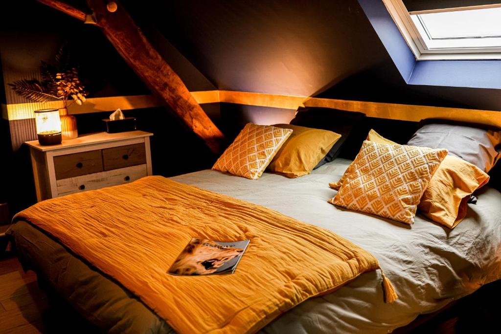 Schlafzimmer mit einem Bett mit gelber Bettwäsche und Kissen in der Unterkunft L'Evasion in Nolay