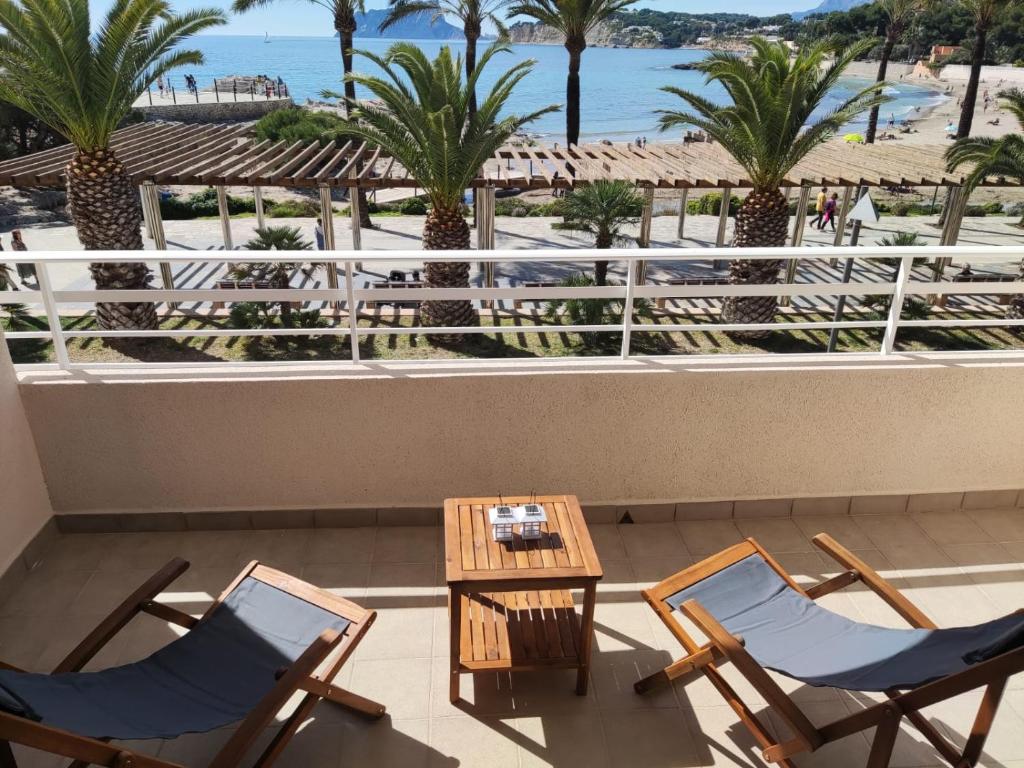 a balcony with two chairs and a table and palm trees at Moraira Beach 1 in Moraira