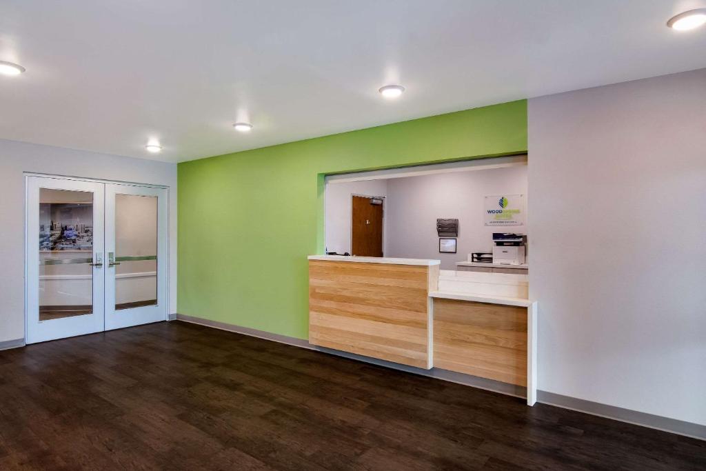 モリスビルにあるWoodSpring Suites Morrisville - Raleigh Durham Airportの緑と白の壁とウッドフロアの空間