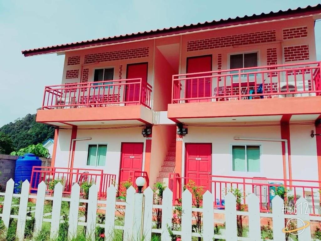 une maison avec des portes rouges et une clôture blanche dans l'établissement Baan Krunah, à Krabi