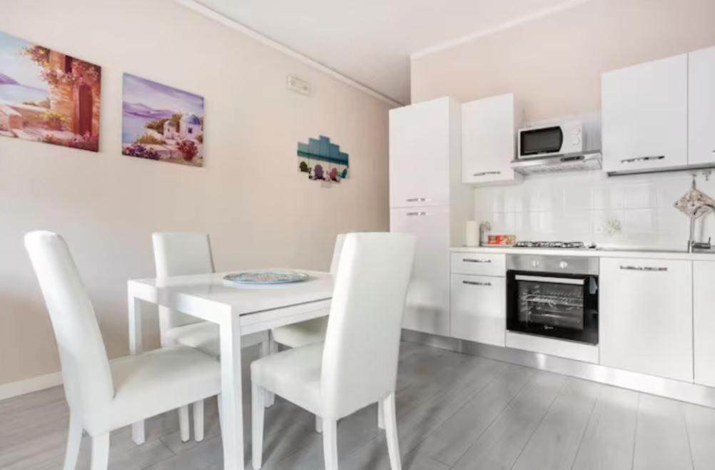 a white kitchen with a white table and chairs at Casa Davide in Sottomarina