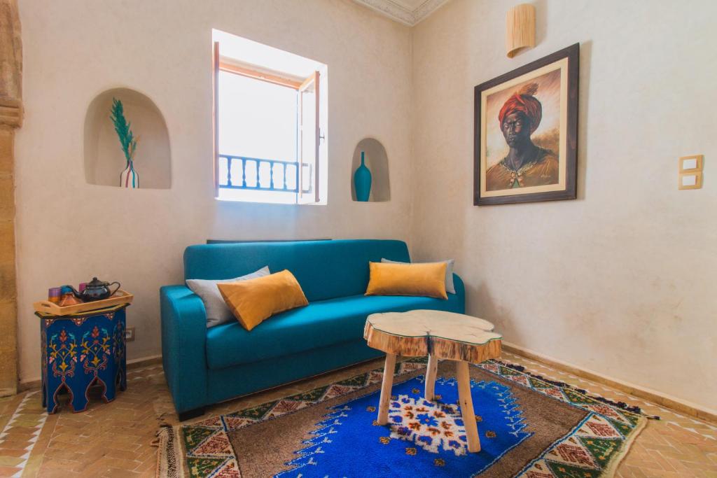 a living room with a blue couch and a table at Stella 1 - joli appartement en médina avec cheminée in Essaouira