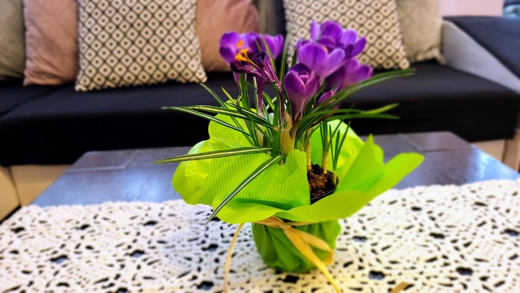 un jarrón verde con flores púrpuras sobre una mesa en Apartament Bystra Woda 28 z garażem, en Zakopane
