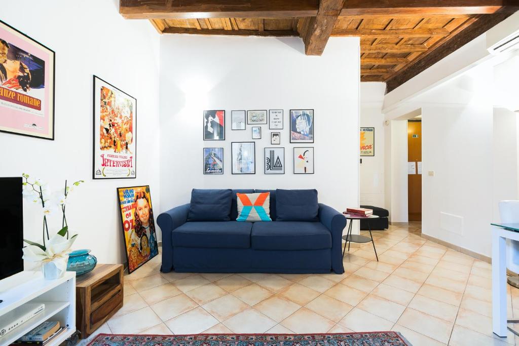 uma sala de estar com um sofá azul e quadros na parede em Suites Campo de' Fiori - Zen Real Estate em Roma