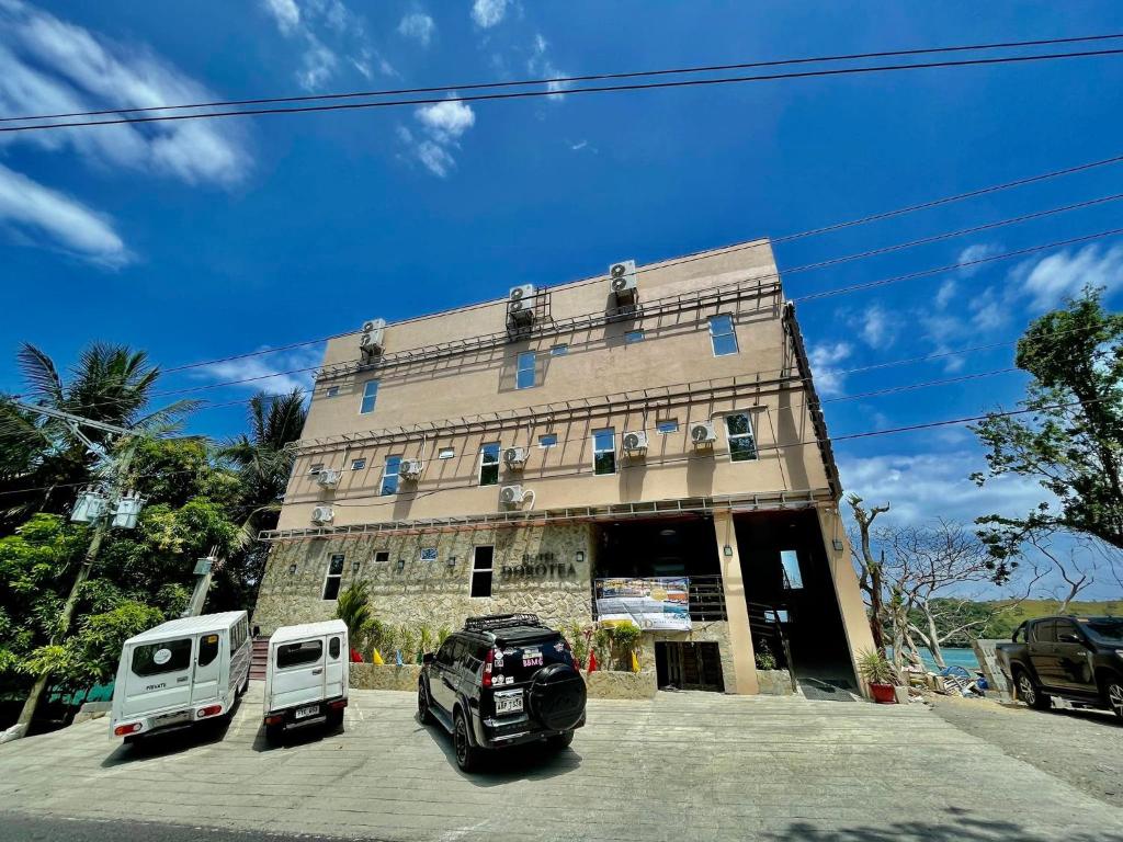 un edificio con dos vehículos estacionados frente a él en Hotel Dorotea, en Puerto Galera
