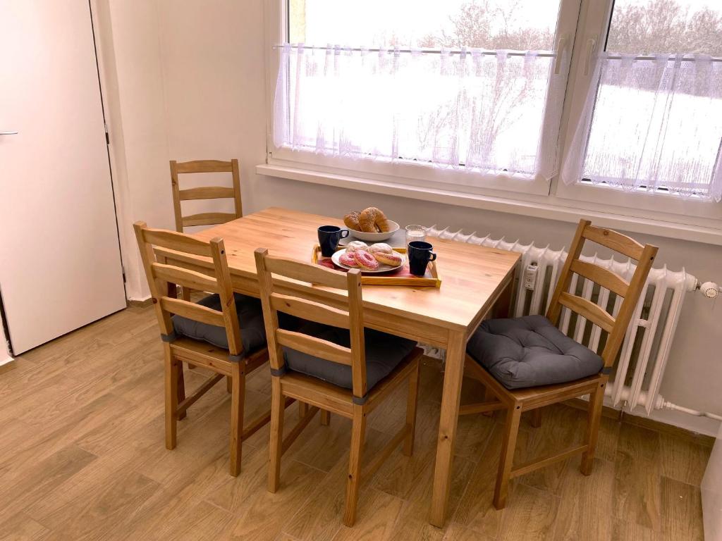 a wooden table with chairs and a plate of food on it at Apartman JakoDoma vlastní parkování u domu ZDARMA in Česká Lípa