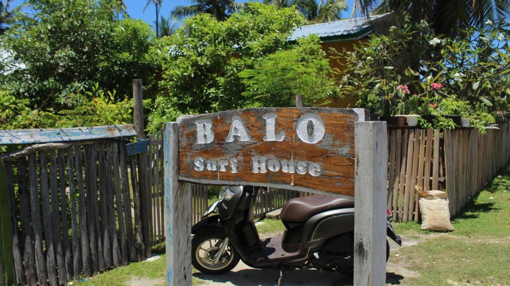 a sign for a scooter parked next to a fence at Balo Surf House in Nembrala