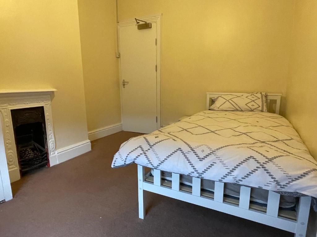 a bedroom with a bed and a fireplace at Rooms In A Victorian Comfortable 4-bedroom house in Milton Keynes Rooms Not En-suites in Wolverton