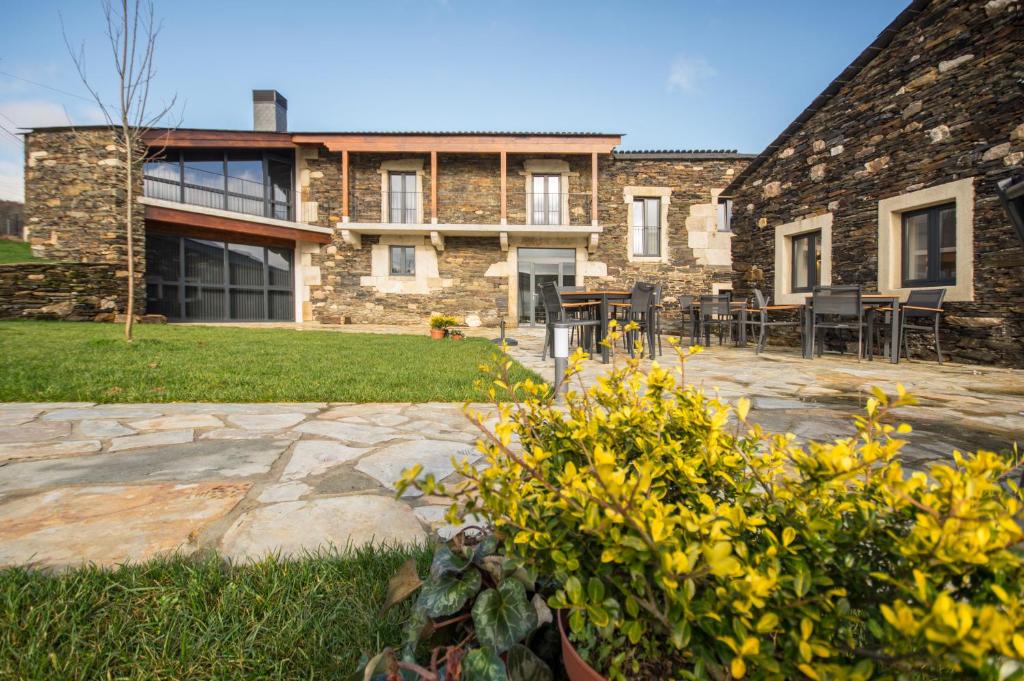 una casa de piedra con un patio frente a ella en Hotel Rural O Cruce do Burgo en Friol