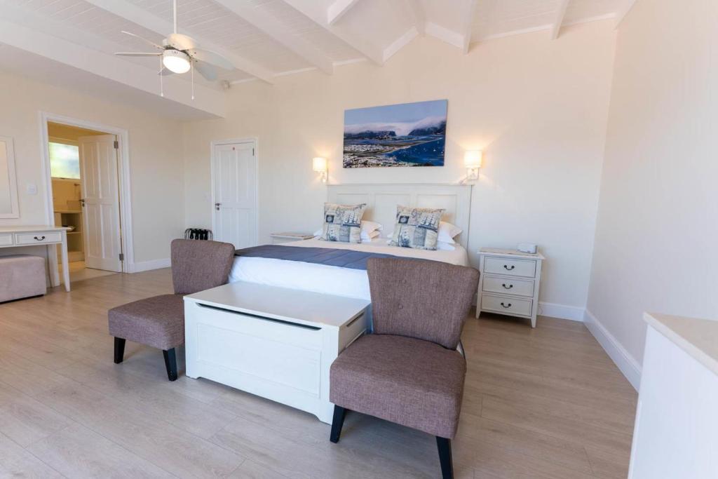 a bedroom with a bed with two chairs and a table at Westhill Luxury Guest House in Knysna