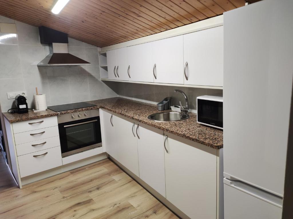uma cozinha com armários brancos e um lavatório em APT 3 Àtic acollidor al Centre de Vic - APTGARBI em Vic