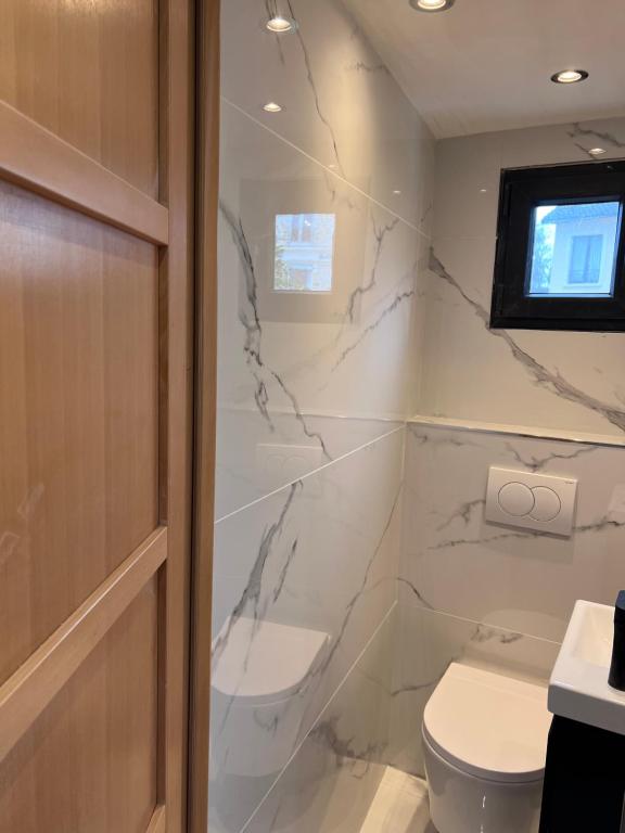 a bathroom with white marble walls and a toilet at Maison Climatisée 04 chambres Paris Disney CDG in Gagny