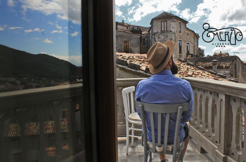 una persona sentada en una silla en un balcón con vistas a una ventana en Albergo Merùo, en Morano Calabro