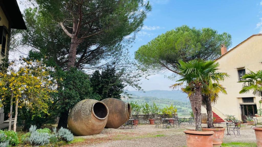 een tuin met twee grote cementpotten en een boom bij Corte Di Valle in Greve in Chianti
