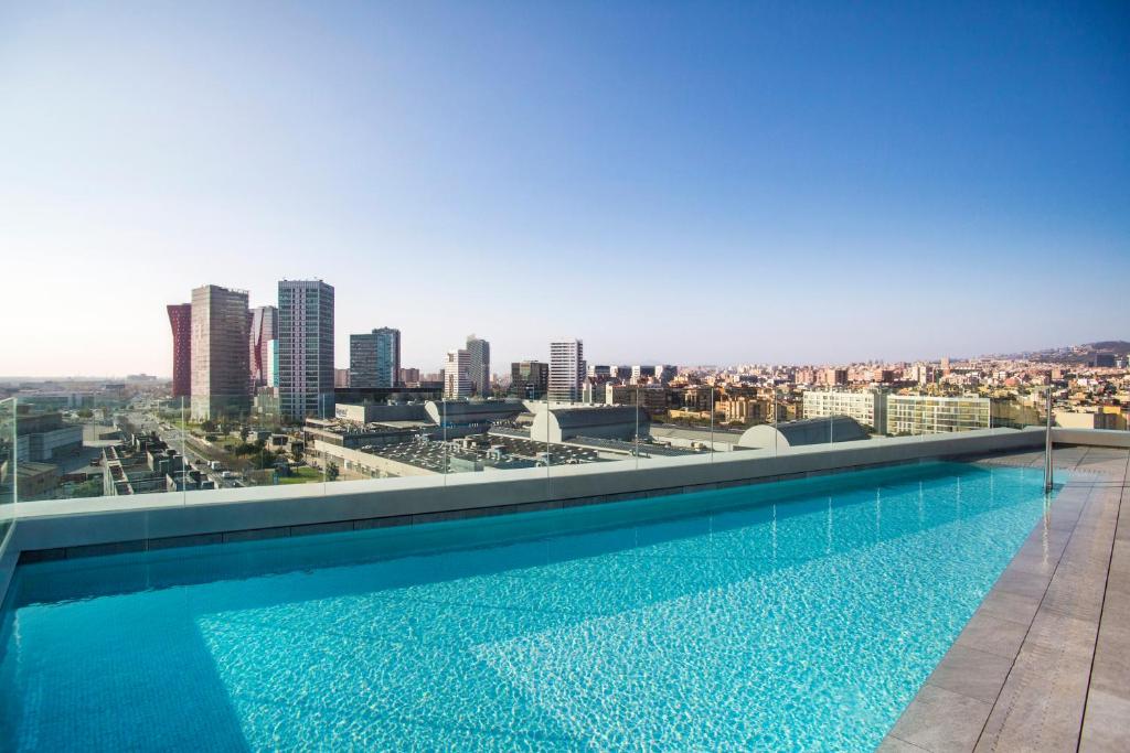 a swimming pool on the roof of a building with a city at Hotel SB Plaza Europa in Hospitalet de Llobregat