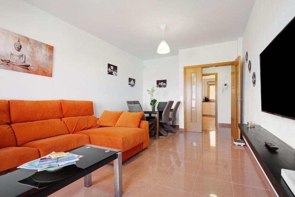 a living room with an orange couch and a table at Casa Rosi 2 in Puerto del Rosario