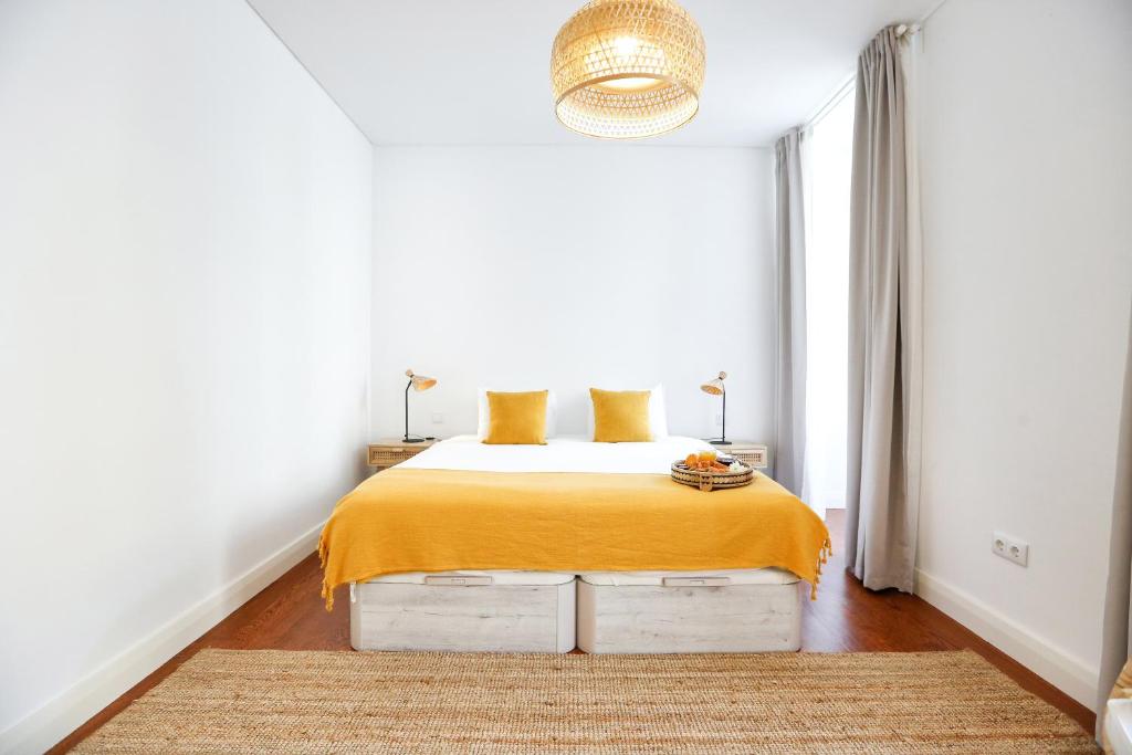 a bedroom with a bed with a yellow blanket on it at Beach Waves Apartment in Faro