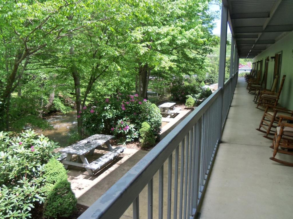 a balcony with a picnic table and flowers and trees at Four Seasons Inn in Maggie Valley