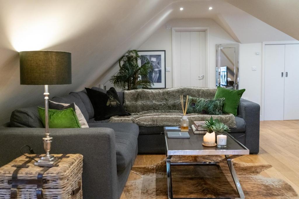 a living room with a gray couch and green pillows at Hertford Barn conversion in Hertford