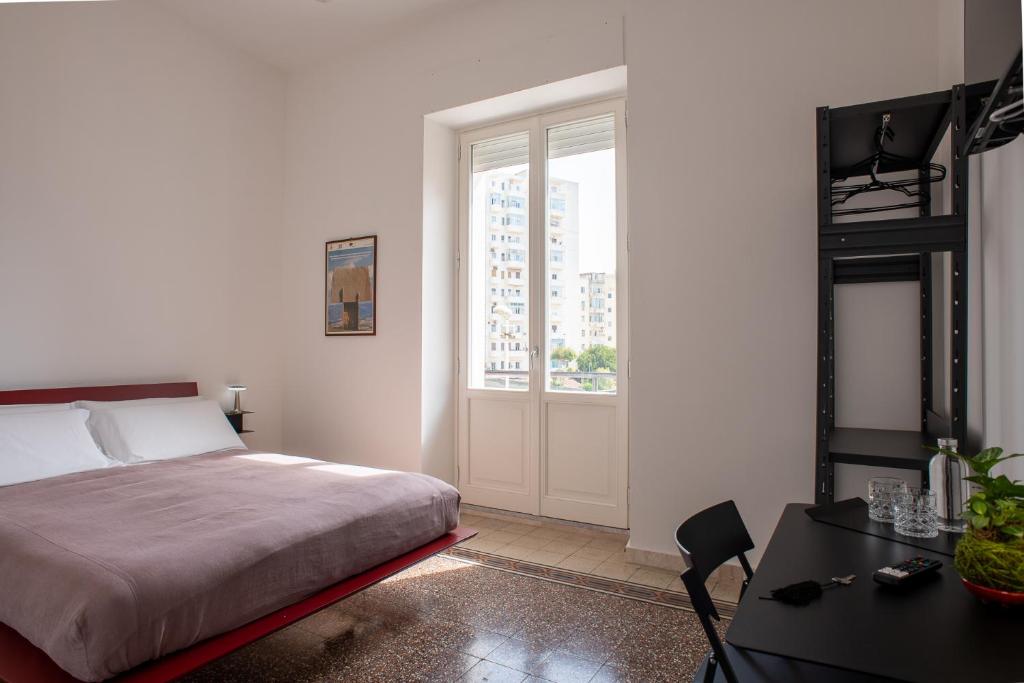 een slaapkamer met een bed, een tafel en een raam bij Al Dio Bes in Cagliari