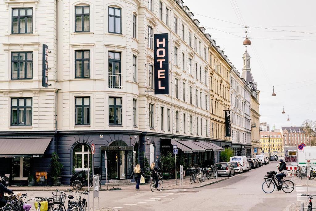 een groot gebouw in een stadsstraat met mensen die fietsen bij Ibsens Hotel in Kopenhagen