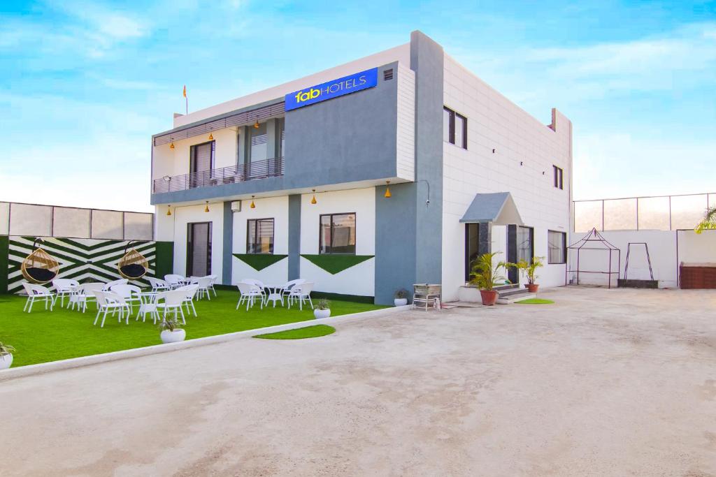Un edificio con mesas y sillas delante. en FabHotel Sky Lark Farm, en Ludhiana