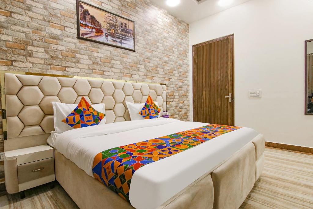 a large bed in a room with a brick wall at FabHotel Sky Lark Farm in Ludhiana