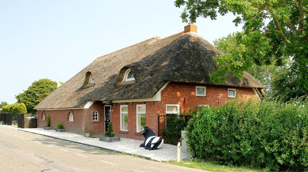 a house with a thatched roof with a whale statue in front at Appartement Greidesicht Kollumerpomp in Kollumerpomp