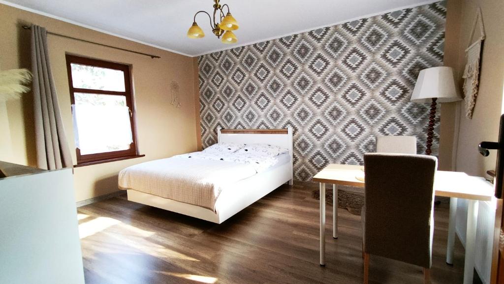 a bedroom with a bed and a table and a window at Willa pod Aniołem in Szczawnica