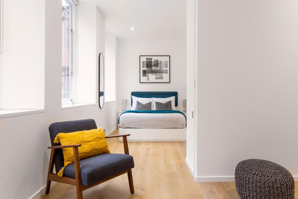 1 dormitorio con 1 cama y 1 silla en 2 Bed 2 Bath Apartment Off Regent Street en Londres