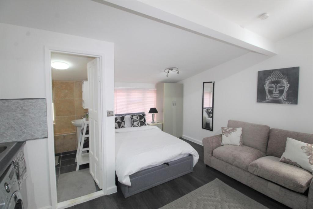 ein weißes Schlafzimmer mit einem Bett und einem Sofa in der Unterkunft Studio 2 min walk to Upton Park Station in London