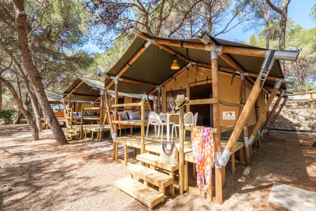 una cabaña en el bosque con sillas y árboles en Camping Torre de la Mora, en Tamarit