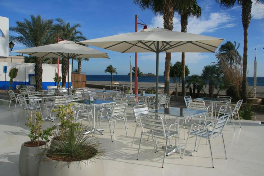 een groep tafels en stoelen met parasols op het strand bij Hotel Las Palmas in Carboneras