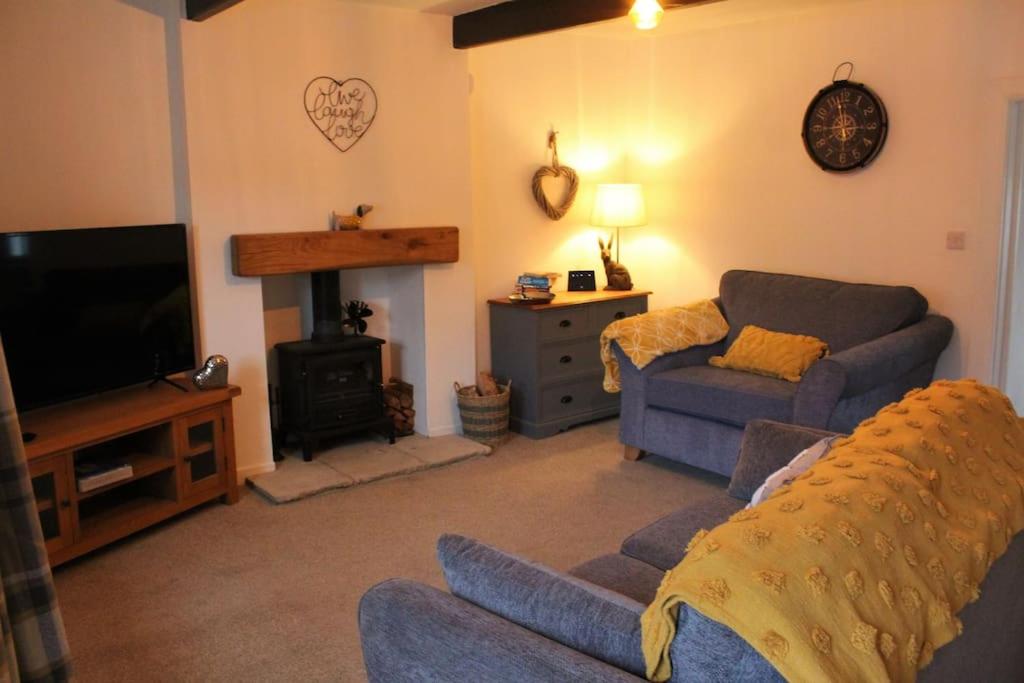 a living room with a couch and a tv at Bumblebee Cottage nestled in stunning countryside. in Barrowford