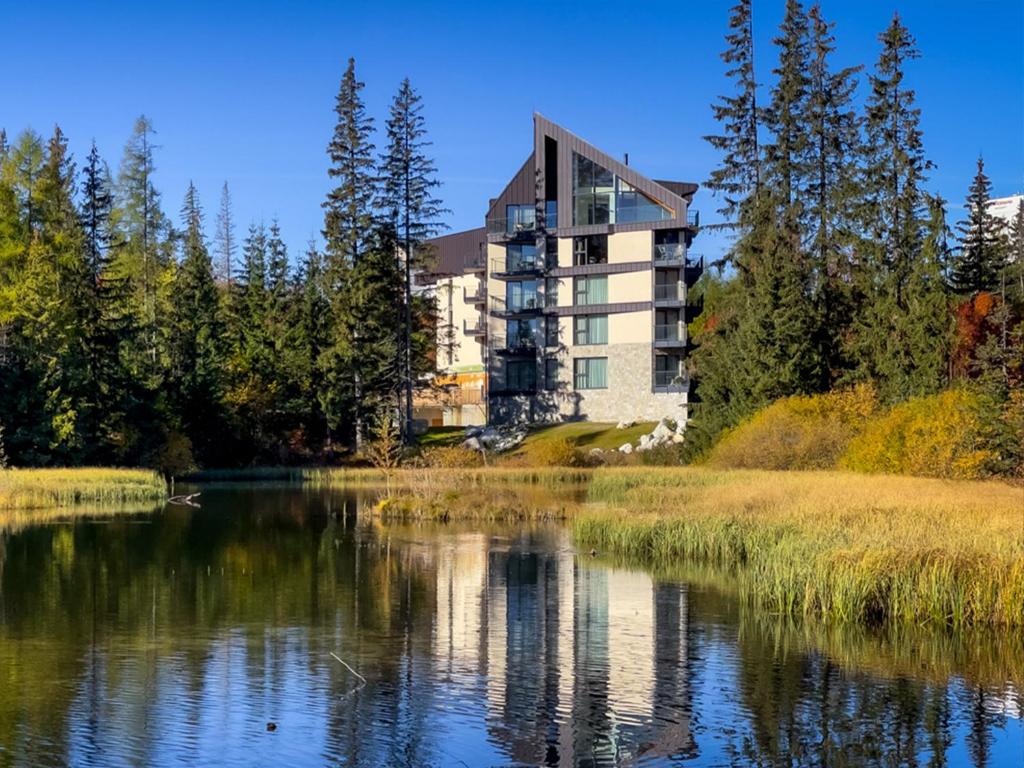 a building next to a body of water at APLEND Lake Resort in Štrbské Pleso